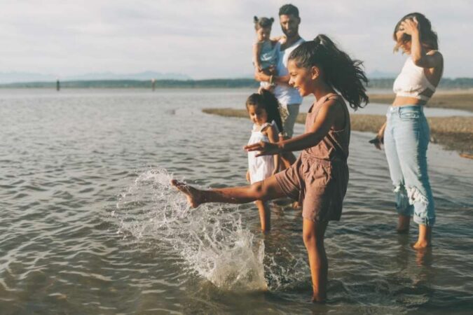 A family splashing in the water during winter beach trips.